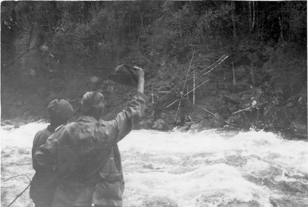 Gjøyst, Tinn. Brotning 1947. To menn vinker til tømmerfløtere på andre siden av elven