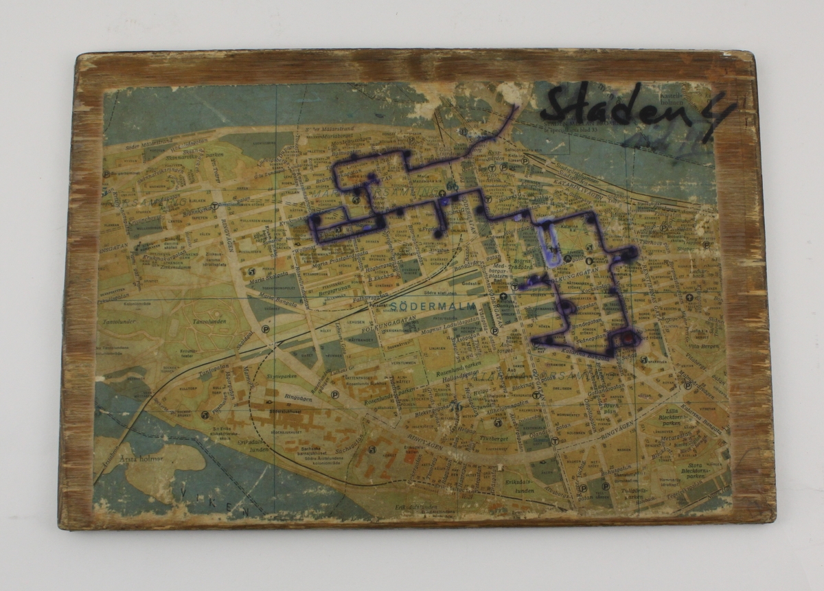 Karta över del av Stockholm, uppklistrad på plywoodskiva. Ena sidan visar Gamla Stan inklusive Riddarholmen, den andra sidan större delen av Södermalm. Färdvägen för tömningen av brevlådor är inritad med kulspetspenna.