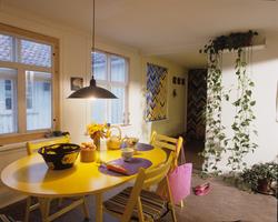 Spiserom med bord og stoler i gult og rullgardin med mønster