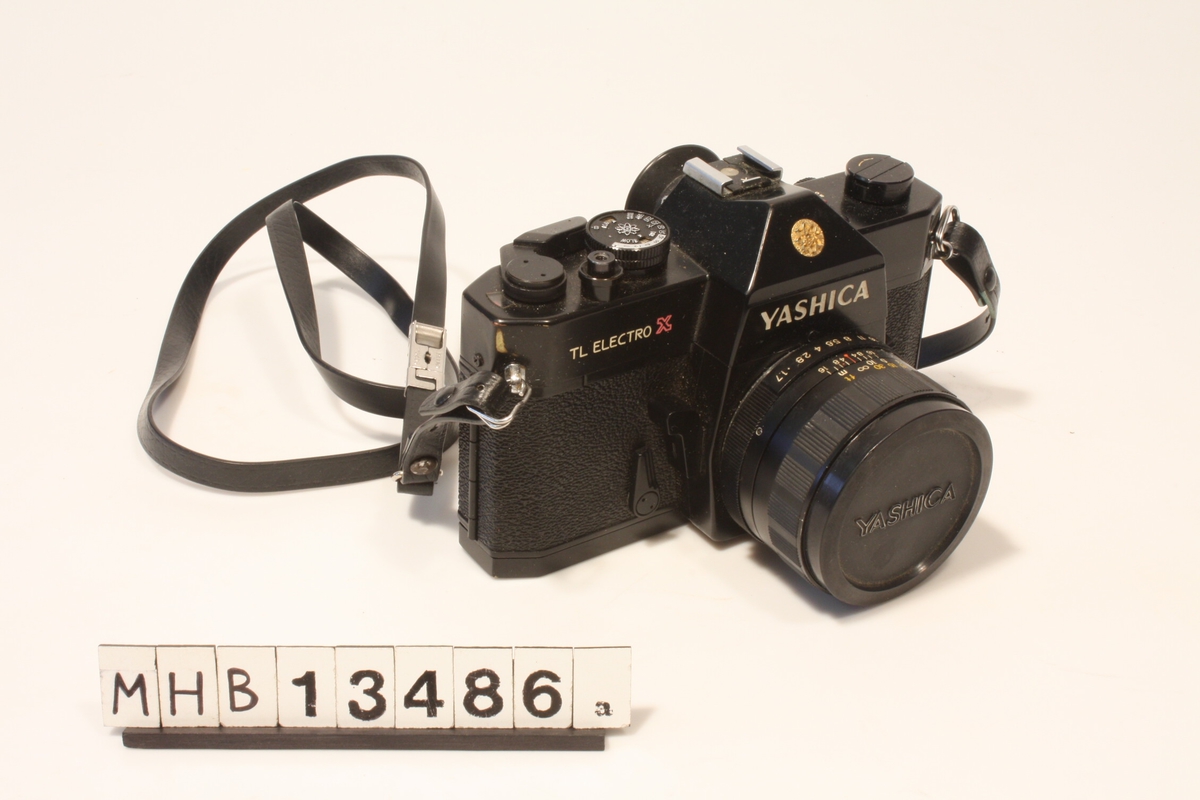 Speilreflekskamera for 135-formatet påmontert 50 mm objektiv og skulderreim.