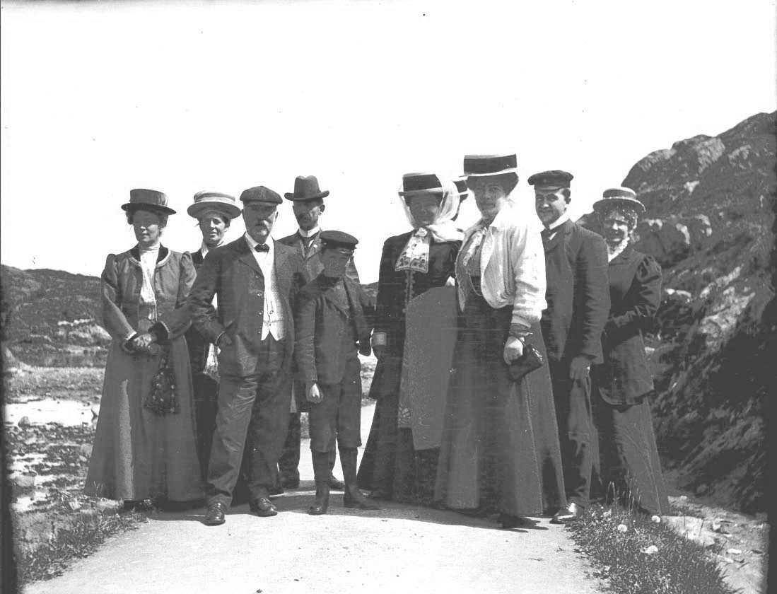 Friluftsliv - gruppebilde - draktskikk. En gruppe mennesker på utflukt. Kvinnene kledd i side kjoler med hatt. Den ene av kvinnene bærer et pledd.