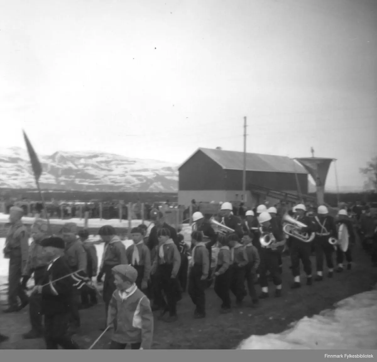 Speiderne foran Garnisonsmusikken (GP) tar av fra Ildskogveien opp til den gamle kirka (kirkebrakka) i Ildskog 17.mai.