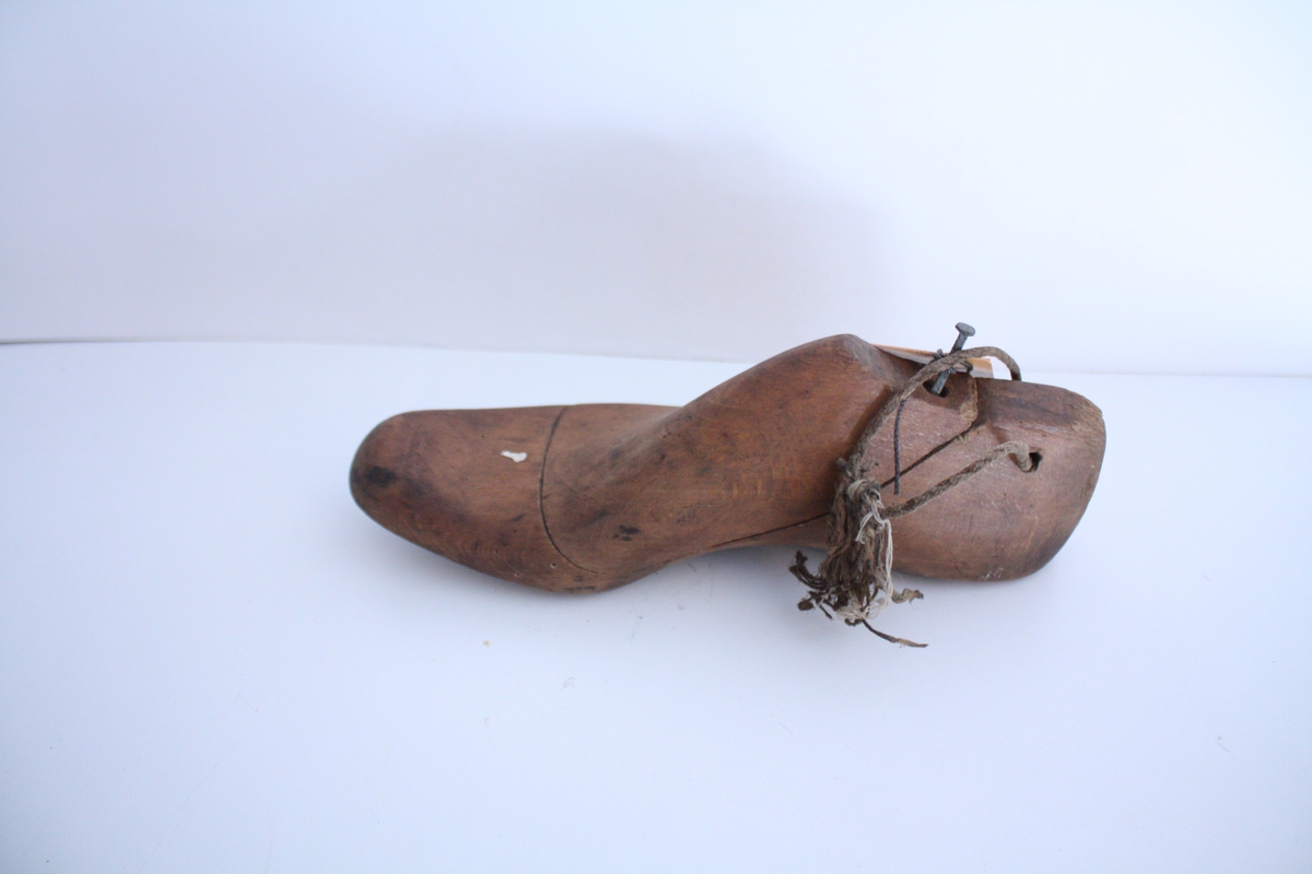 En høyre skoform. Skoformen er todel, der vristen er et løst stykke som holdes på plass med en spiker. Et tynt tau er festet gjennom et hull på hælen.