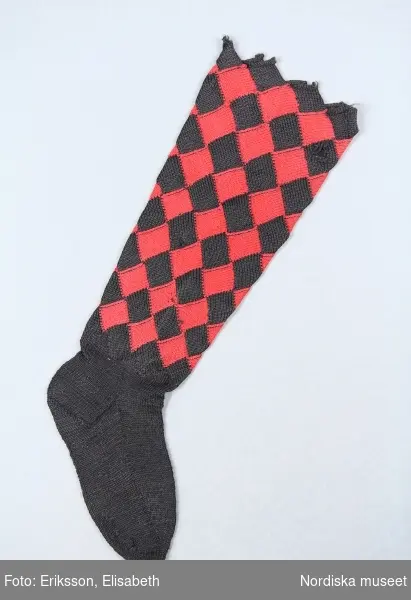 A-B. Strumpa för kvinna, ett par.
S-tvinnat ullgarn.
Stickad i slätstickning, foten enfärgad svart, skaftet stickat i näverstickning rutigt i rött/svart.
/Berit Eldvik 2002