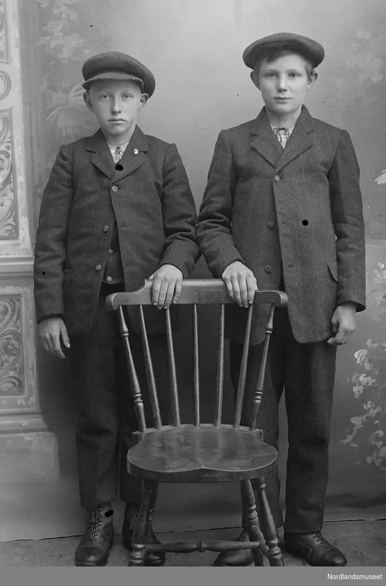 Portrett. 2 gutter, ca. 10-12 år. Står bak en stol. Luer.