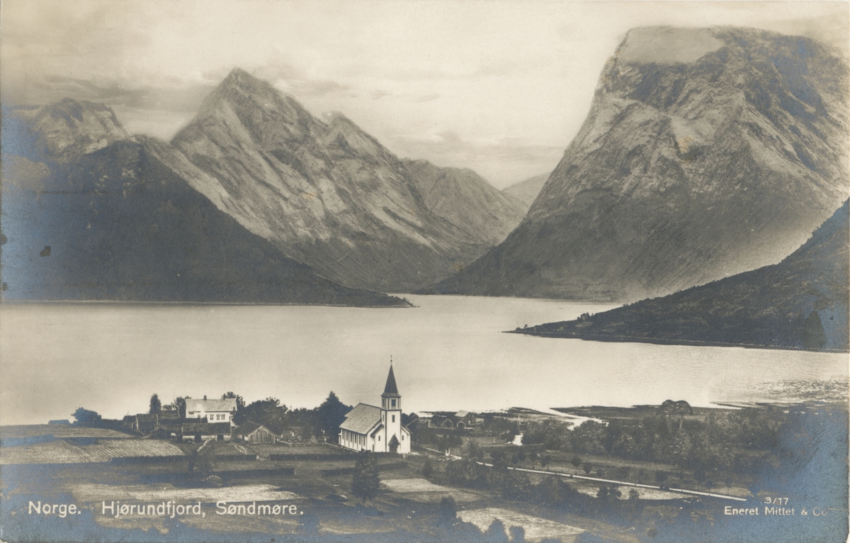 Prospektfotografi over Hjørundfjorden med Sæbø og Hjørundfjord kirke i forgrunnen.