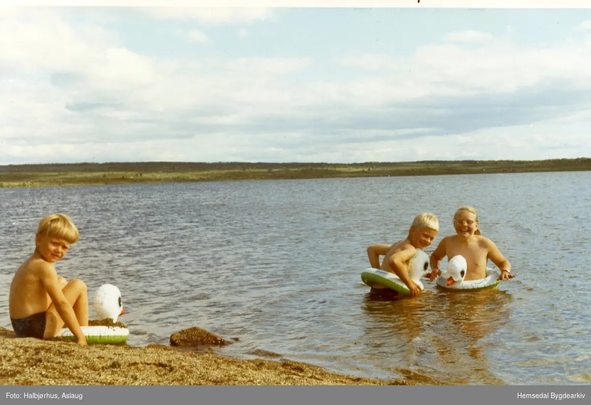 Badetemperatur i Rensenvatnet i 1971. Nils Halbjørhus på land, medan syskjena, Jon og Kari, bløyter seg.