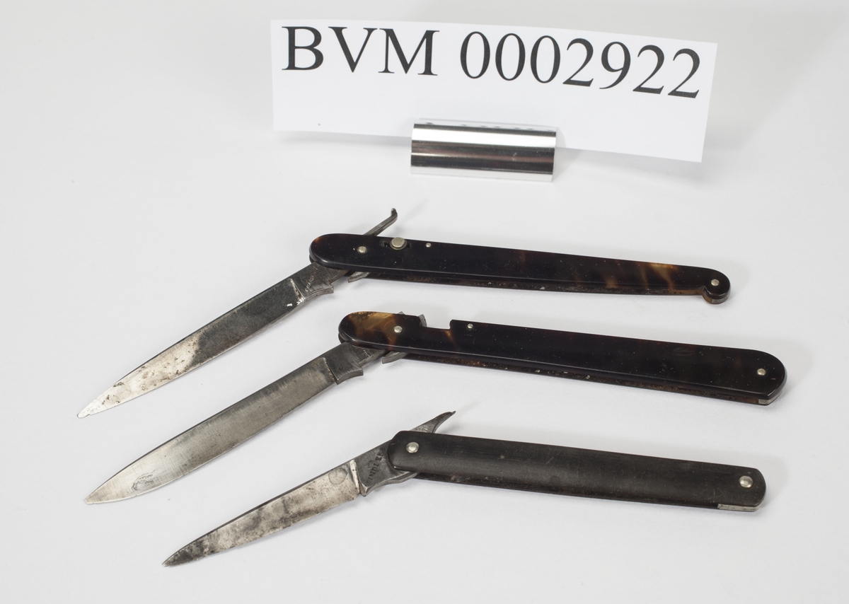 Tre kirurgiske foldekniver av samme type. To med låsemekanisme, hvorav den ene er defekt. Den tredje kniven er uten låsemekanisme.