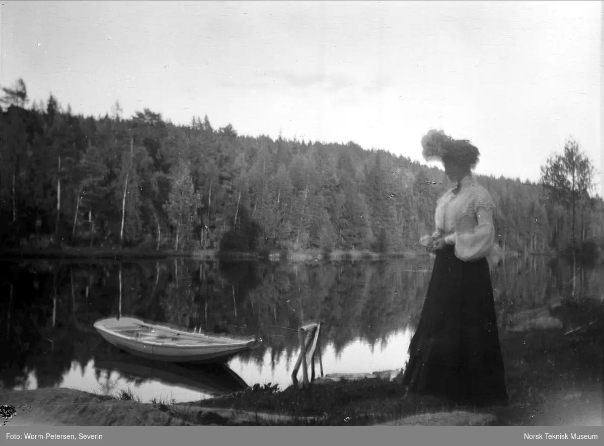 Kvinne ved innsjø med robåt