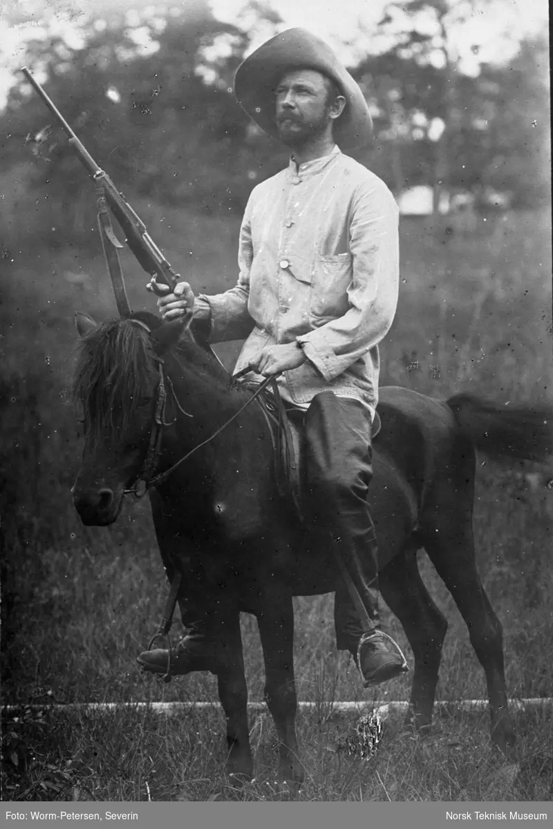 Mann (vestlig) til hest med gevær, trolig Kina eller Thailand