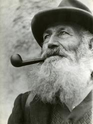 Portrett av man med skjegg som røyker pipe.