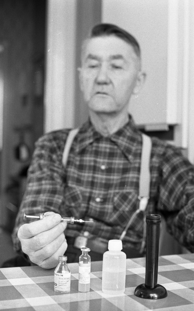 Diabetiker, 5 februari 1966

En äldre man i en rutig skjorta och hängslen håller en spruta i sin högra hand. Framför honom på bordet står en liten flaska fylld av insulin samt ytterligare två flaskor. Mannen har diabetes.