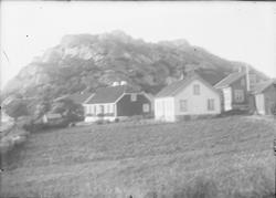 Hus i en grend i et landskap ved kysten. I forgrunnen sees e