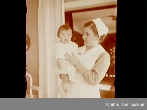 Rumsinteriör, en kvinna och en liten flicka.
Barnsköterskan Annie (Titti) Wallin och Barbro Thermaenius