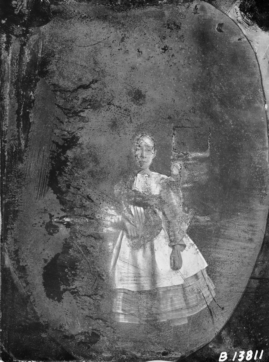 Kvinna (flicka) poserar framför kameran. Troligen från 1850-talet