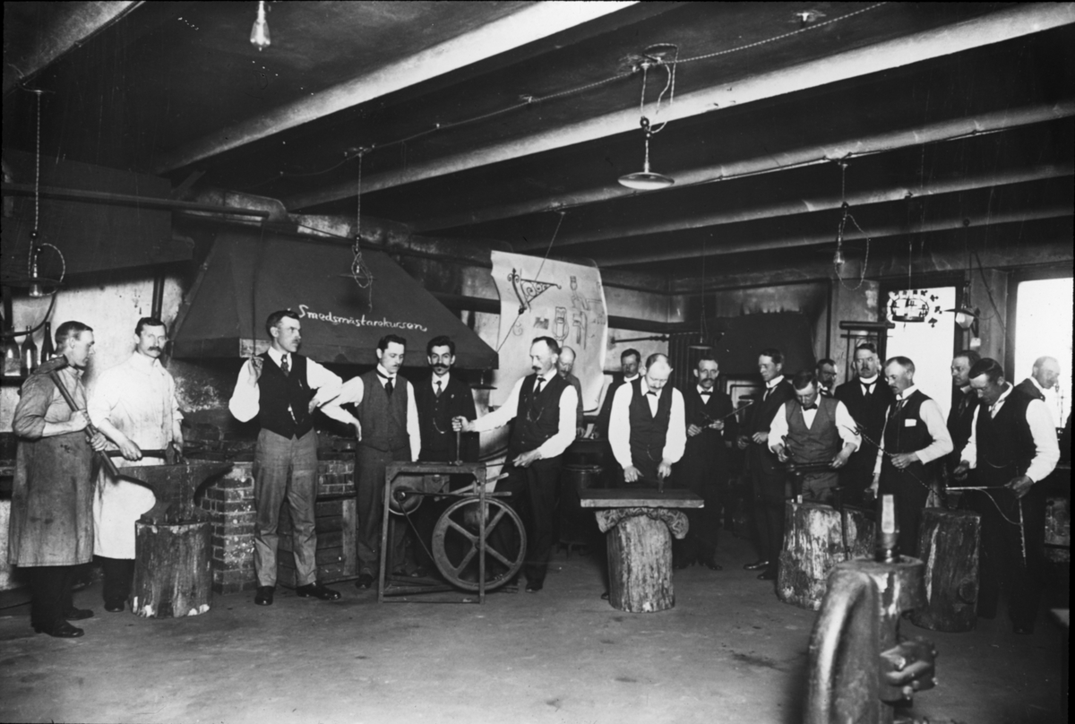 Bild visande skråverksamhet.
Gruppbild av män i lörosal, smeder 1918.