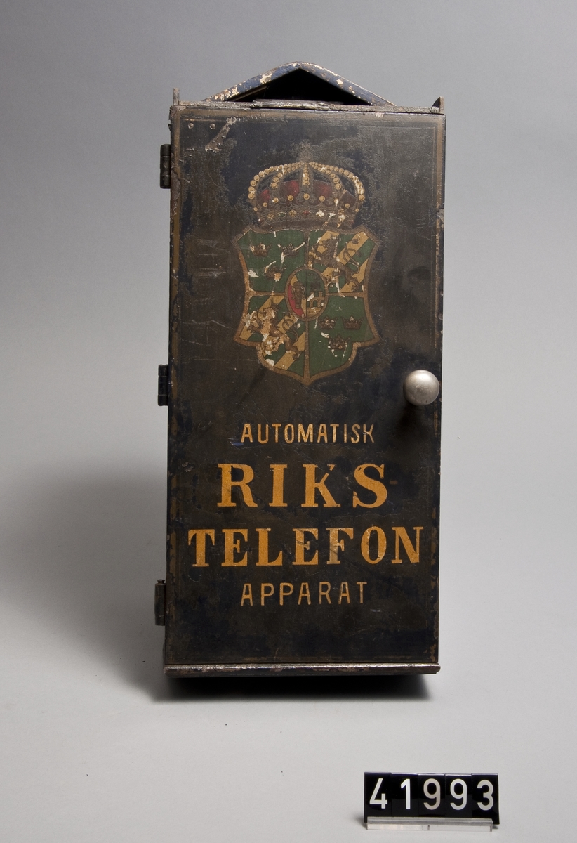 Stolpapparat med emblem, s.k. "Automatisk Rikstelefon Apparat" (samtalsautomat).
