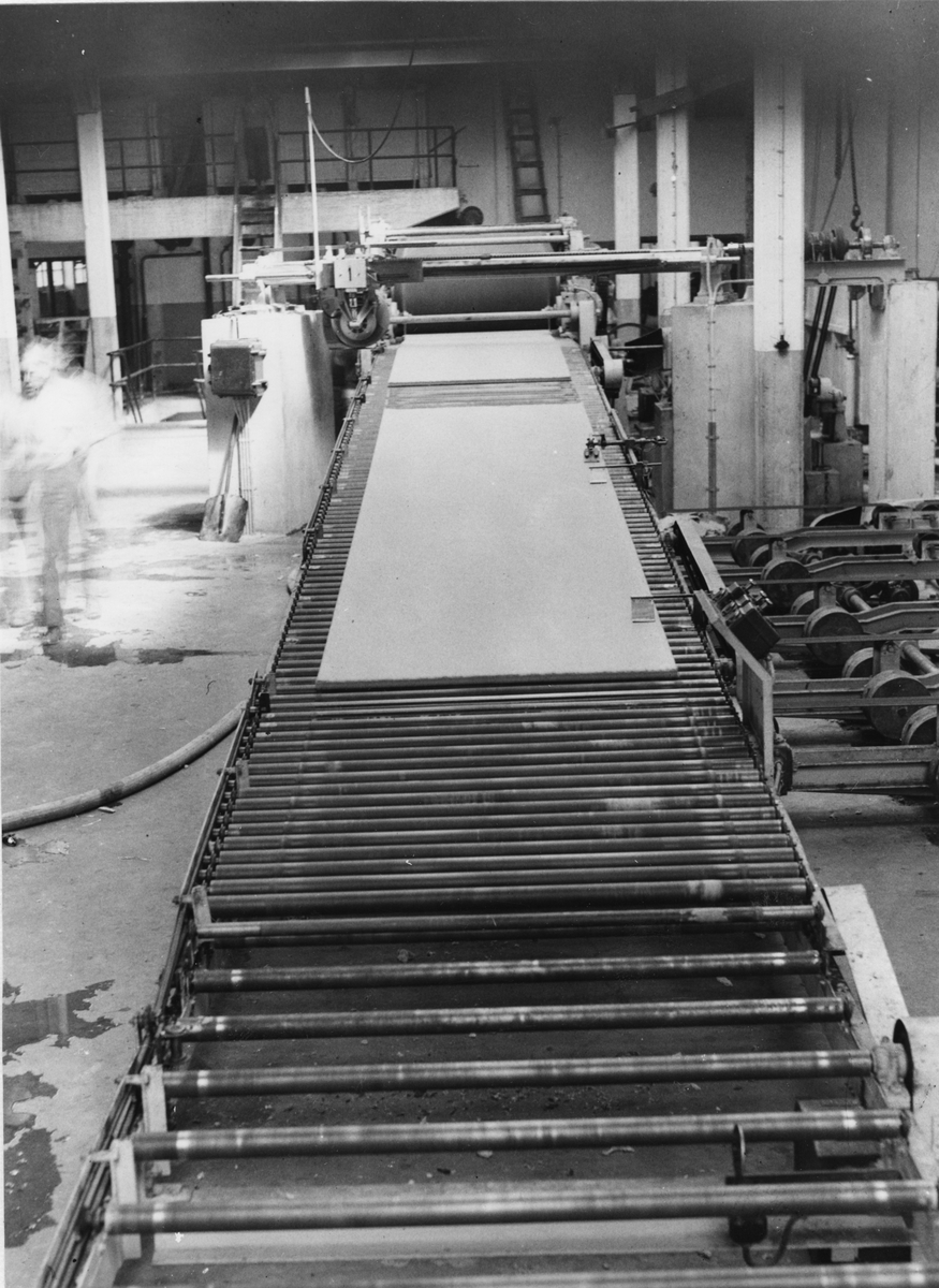 Karlholms Aktiebolag. Formningsmaskin för träfiberplattor. Plattorna  rullar ut ur maskinen till torken.