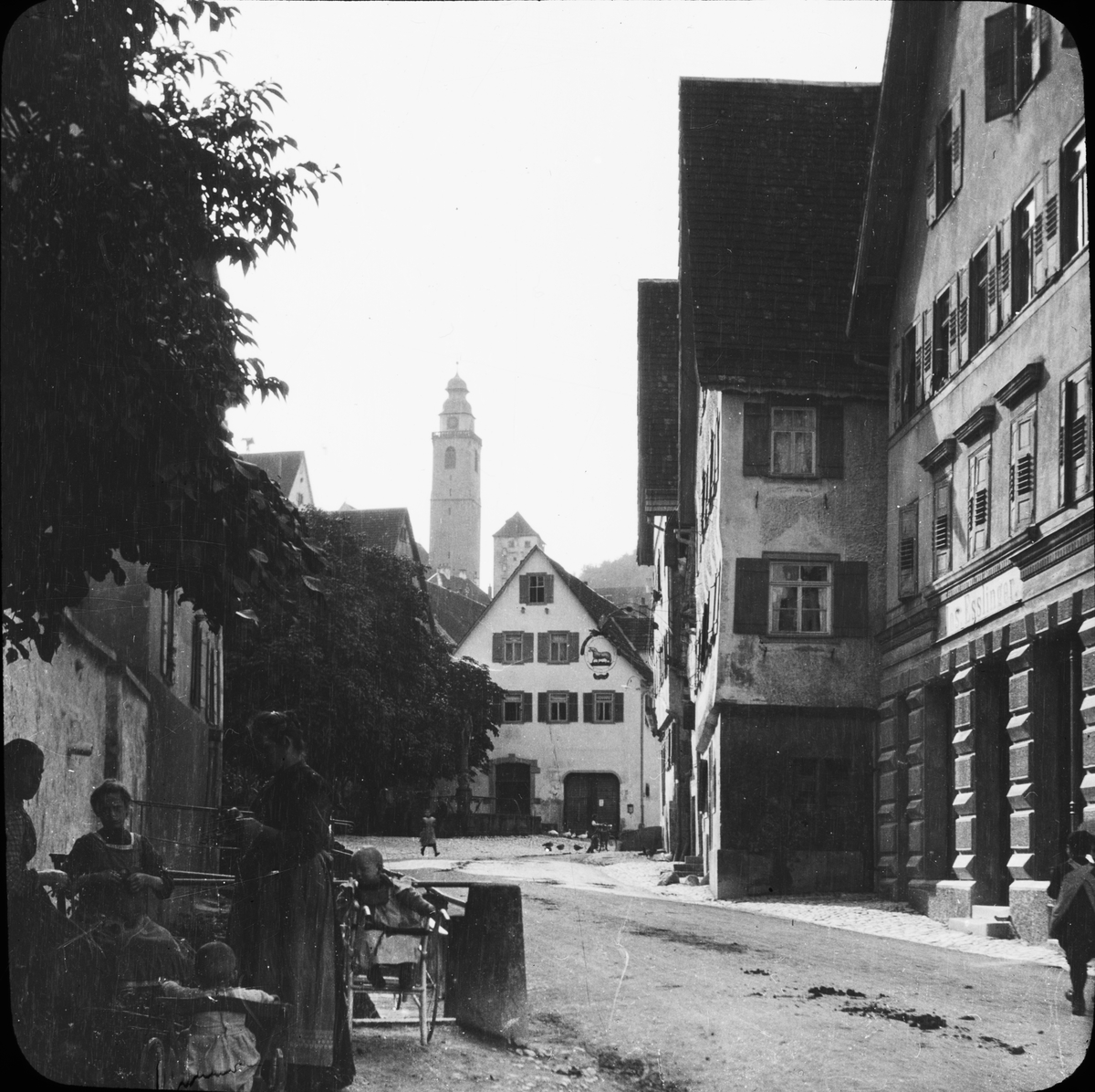 Skioptikonbild med motiv från gata i Horb am Neckar med tornet till Stiftskirche i bakgrunden.
Bilden har förvarats i kartong märkt: Resan 1908. Horb 7. VIII.