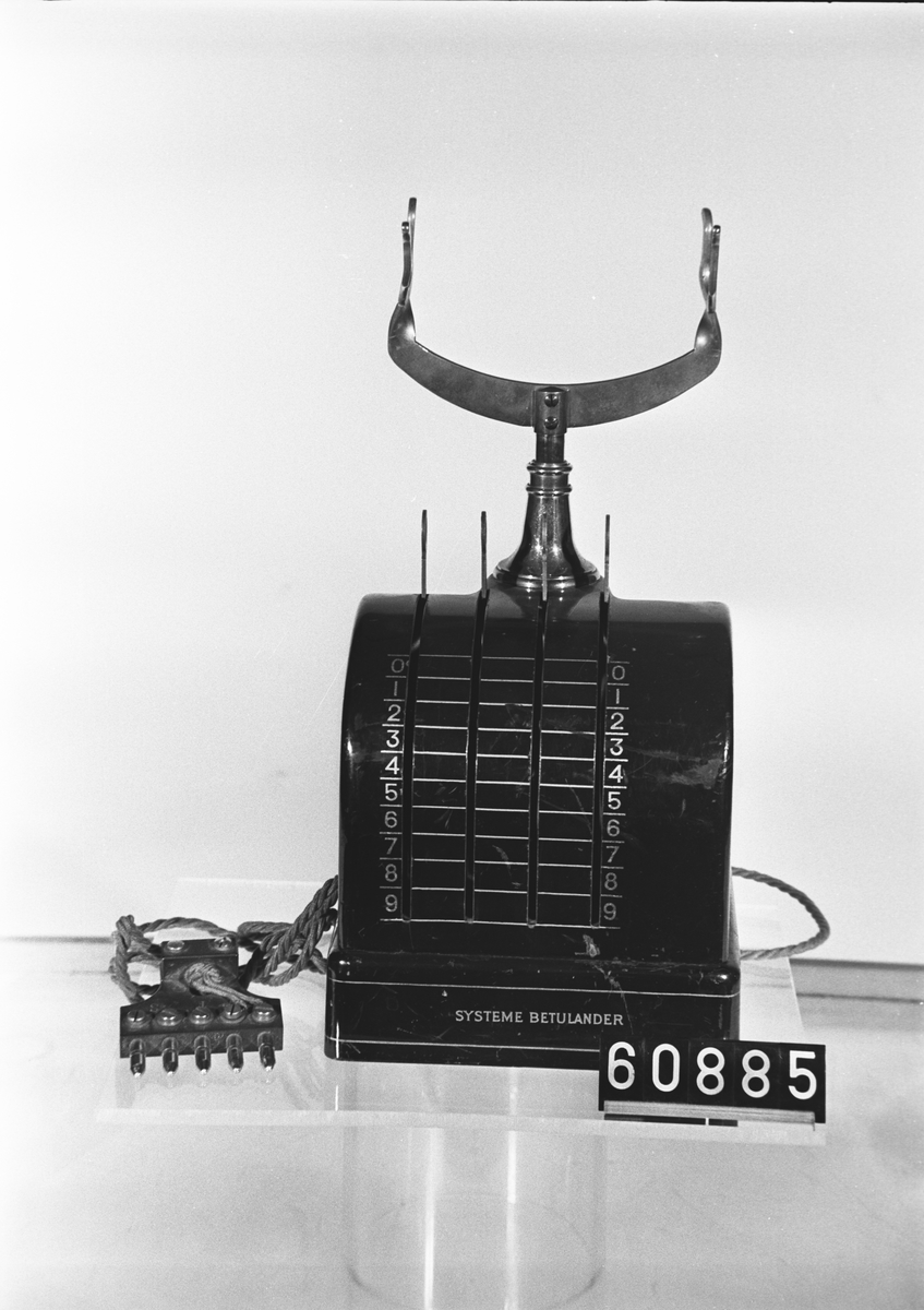 Automatisk telefonapparat, svartlackerad bordsmodell med hävarmar istället för fingerskiva.