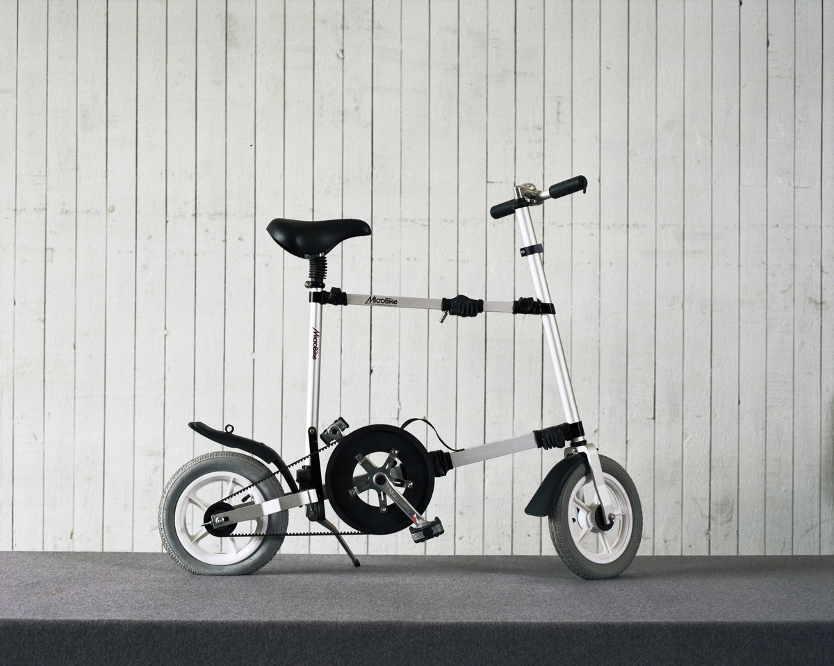 Cykel, hopfällbar låghjuling av plast, gummi och aluminium. Drivs av kevlarförstärkt kuggrem. Hjulbas: 90 cm.
Tillbehör: Fast insexnyckel: 6 mm.