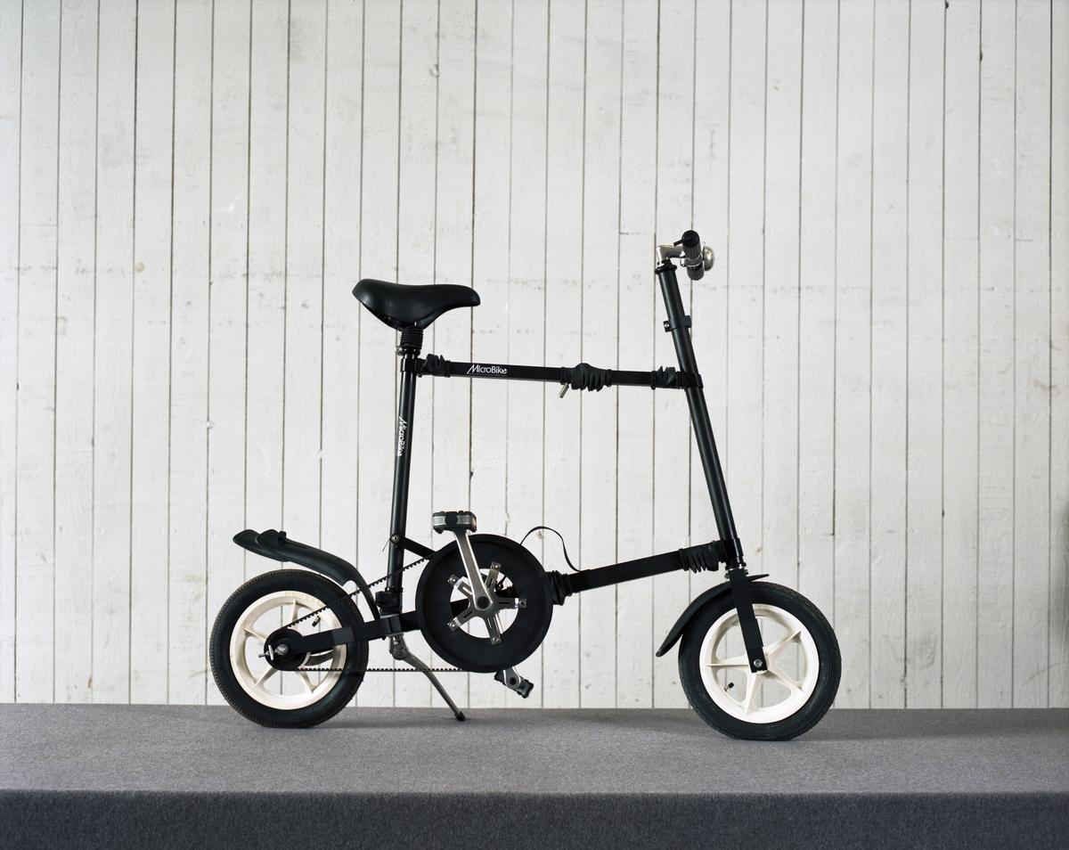 Cykel, hopfällbar låghjuling av plast, gummi och aluminium. Drivs av kevlarförstärkt kuggrem. Hjulbas: 90 cm. Defekt baknav, högväxel.
Tillbehör: Fast insexnyckel: 6 mm.