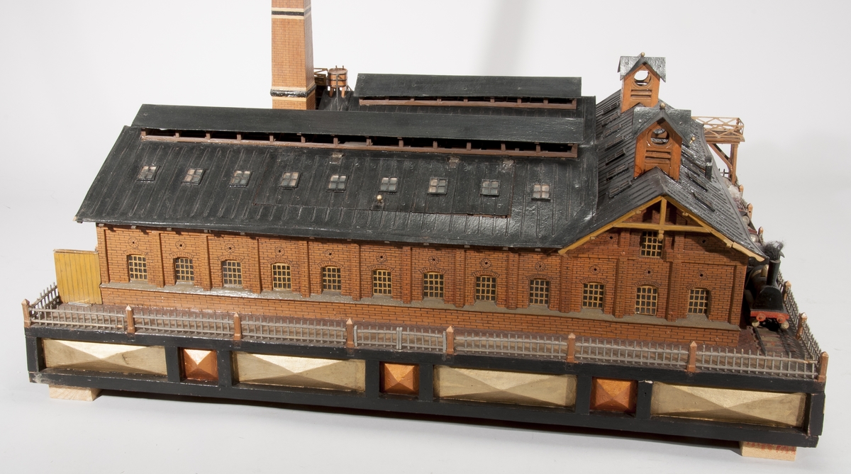 Modell av kopparextraktionsverk av trä och glas. Föremålet föreställer en fabriksbyggnad med hög skorsten inkl. rökmoln. Ett lätt ånglok med fyra malmvagnar ingår.
Tillbehör: Glasmonter.