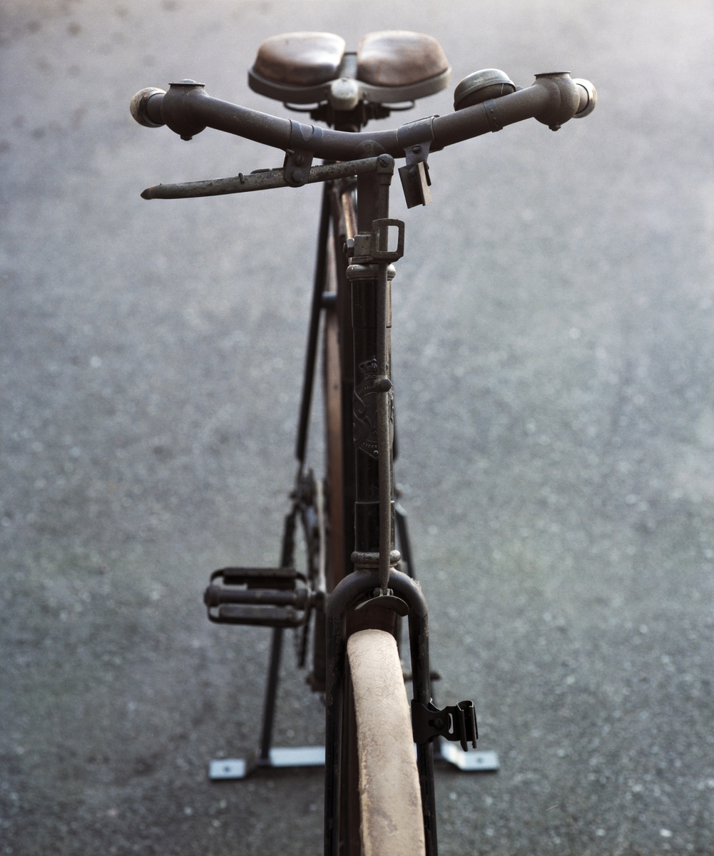 Tvåhjulig cykel med vertikaltrampning, herrmodell. Cykeln är utrustad med två sabelfästen. Träfälgar och träskärmar. Amerikansk ringklocka.
Tillbehör: Verktygsväska.