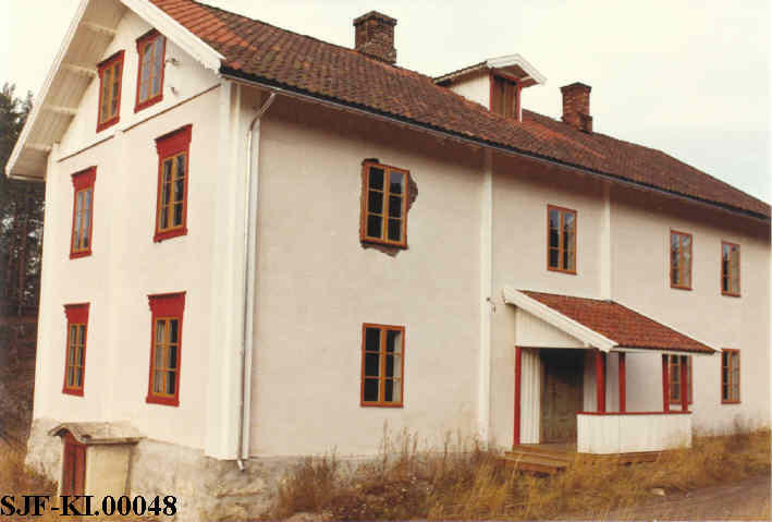 Hvit murbygning med rød ramme rundt vinduene.