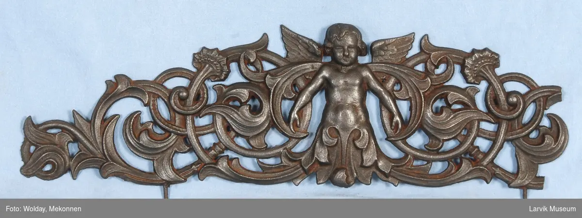 Midtstil barnefigur i form av engel omsluttet med blad-ornamentikk