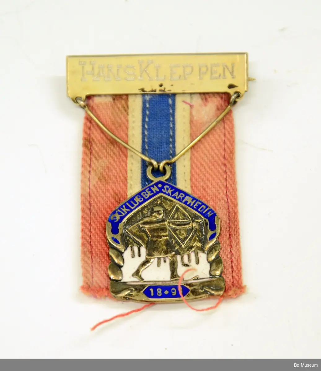 Medalje med innskrift:
HANS KLEPPEN
og SKIKLUBBEN SKARPHEDINS (1891) merke/logo
Bånd i rødt, hvitt og blått, svært falmet og gulnet.