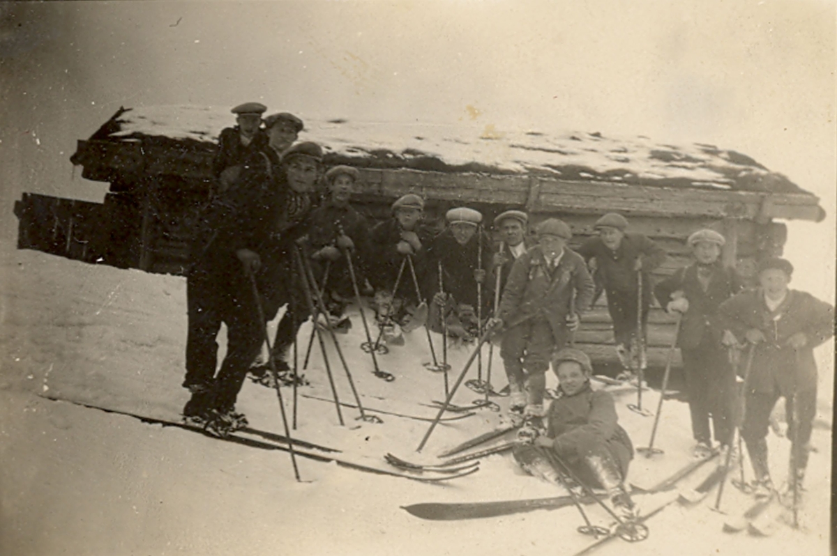 Ungdomar på ski framfor ein stulsbygning.
Ukjente personar og stad.
Amatørfoto.
