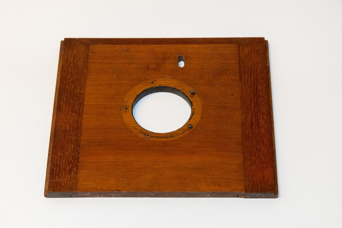 Gruppering med fotokamera i oppbevaringskasse, separat metall-lokk, stereolinse, lause delar som negativplate, mattskive, blendarsett og diverse smådelar.