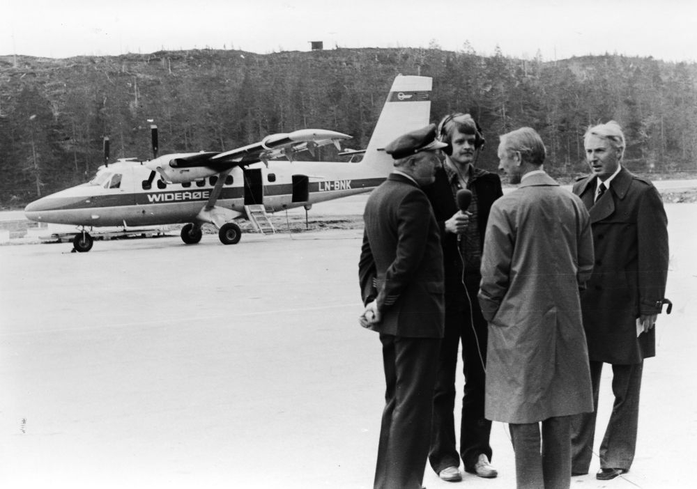 Lufthavn/Flyplass. Fire personer, samlet ved et fly, LN-BNK, DHC-6 Twin Otter fra Widerøe. To personer fra Widerøe blir intervjuet av en journalist.
