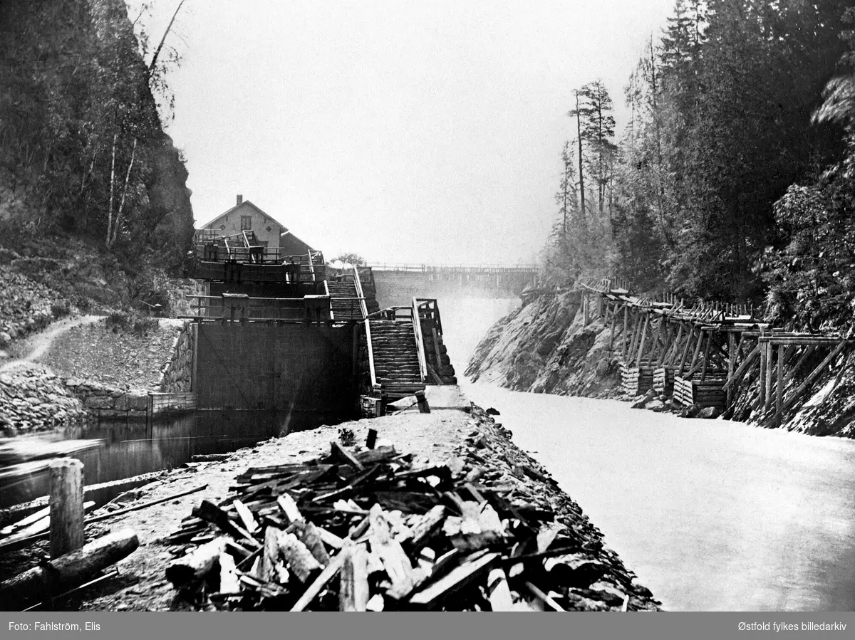 Krappeto sluser i Halden  ca. 1880-85. 
Krappeto sluser sett nedenfra. Slusen til venstre, elveløpet til høyre. Til høyre på bildet er det endel tømmerkar og stillas. Dette er fra riving av fløtningsrenna som ble benytta inntil slusene i Stenselva ble gjenoppbygd, innviet 12. juni 1877. Krappeto dam er den gamle tømmerdam fra 1865 som ble ombygd 1892-94 til stendam.