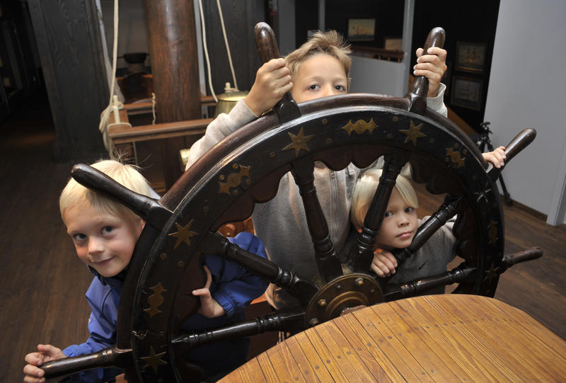 tre barn rundt et seilskute ror.