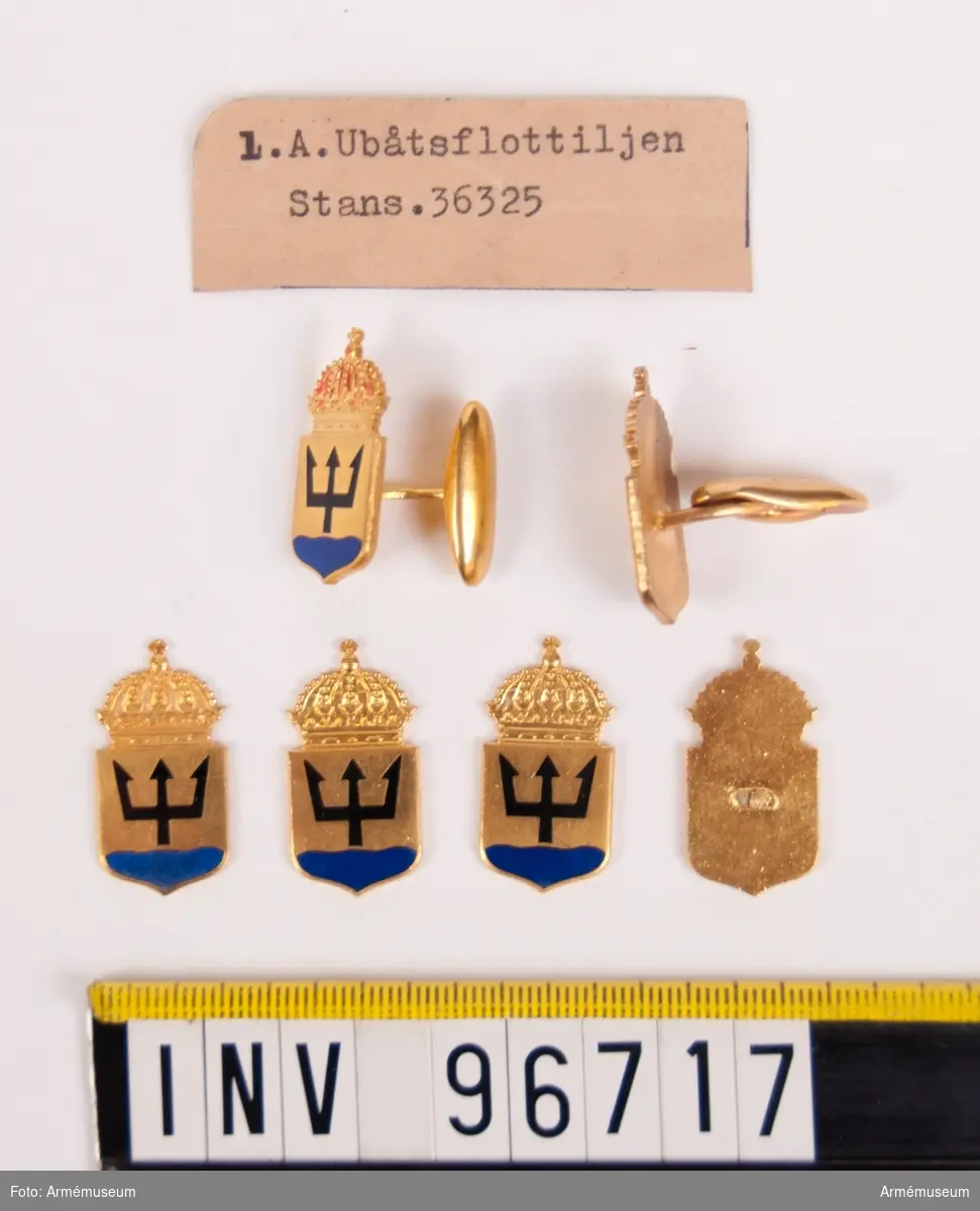 Manschettknappar i guld för 1:a ubåtsflottiljen.
Två manschettknappar samt fyra lösa delar.
Stans nr 36325.