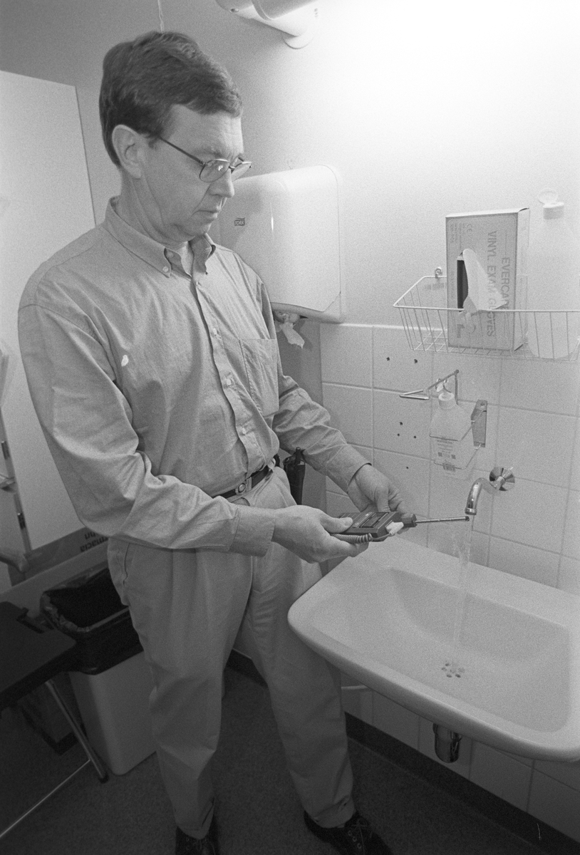 Driftingenjör Jan-Erik Evebjörk berättar att kranarna i 60-, 70-, och 85- husen spolas med lägst 70 gradigt vatten för att rensa bort legionellabakterier, Akademiska sjukhuset, Uppsala 1997