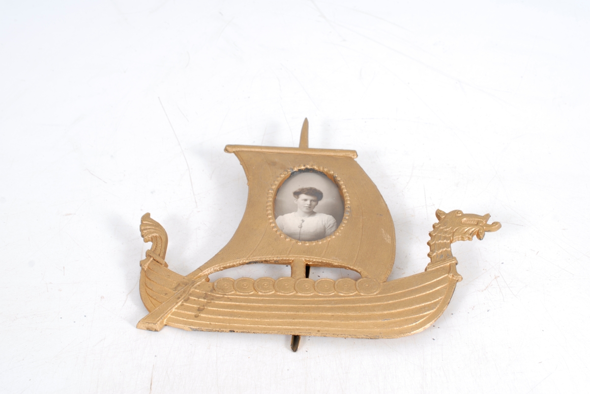 vikingskip med dragehoder og fotografiet som oval utskjæring i seilet.
