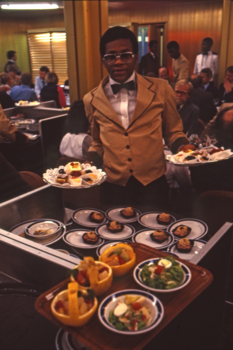Servitøren viser frem et utvalg retter i restauranten ombord i S/S ‘Norway’ (ex. ‘France’)(b.1961, Chantiers de l’Atlantique).