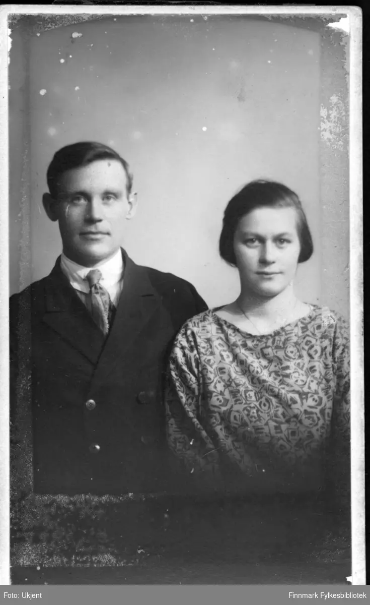 Et portrett av Ingvard og Astrid Mathisen, et ektepar. Ingvard er kledd i dress: han har på seg jakke og slips. Astrid har på seg en dekorativ bluse og et smykke rundt halsen.