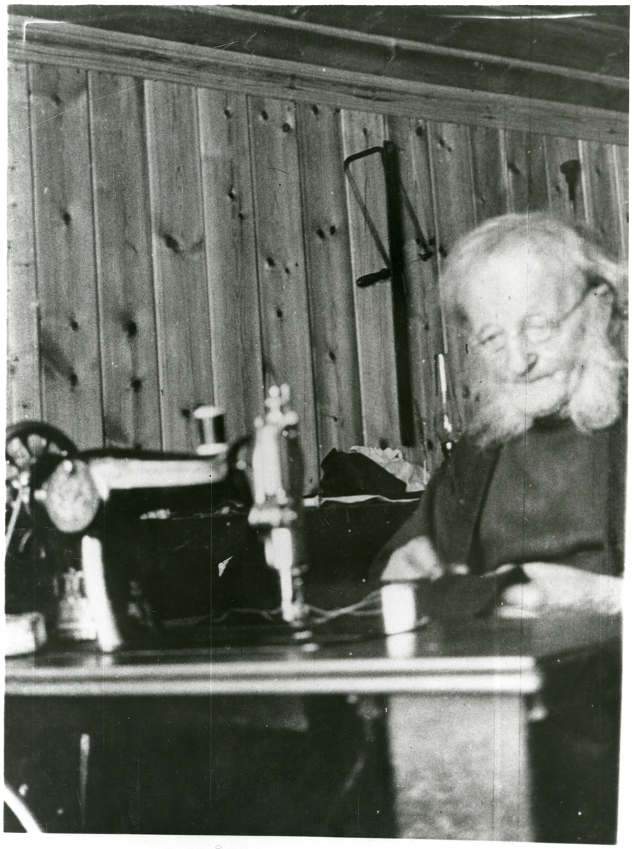 Portrett av skredder Gudbrand O. Skimten, sittende ved sin symaskin.