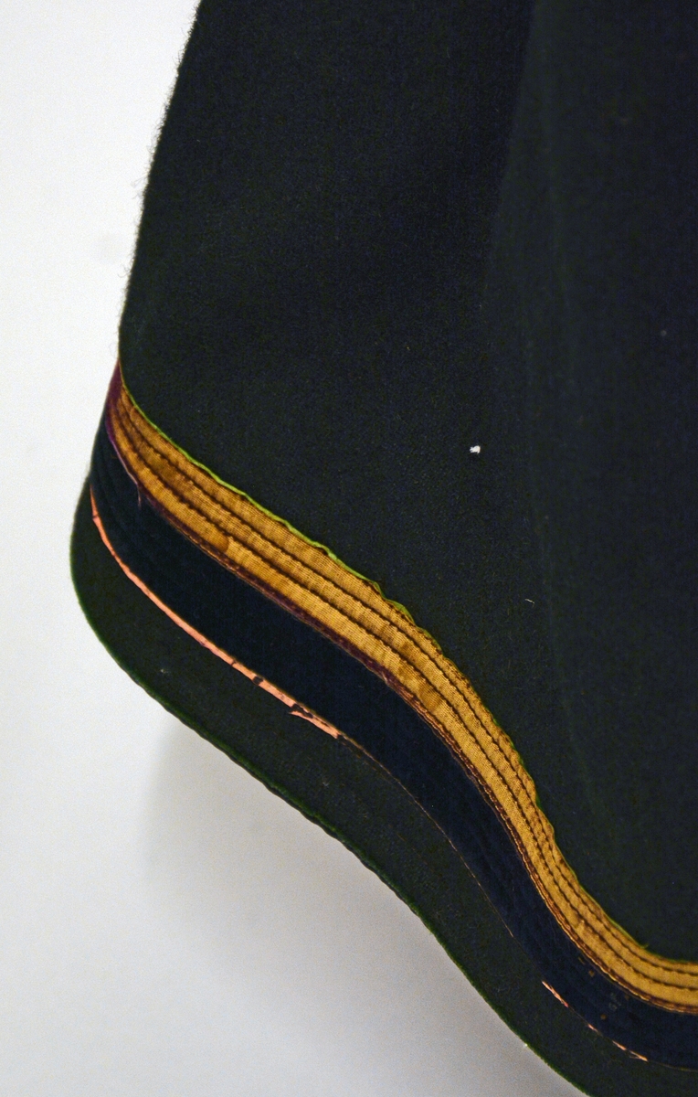 Fra protokoll: Kvindedragt, oprindelig syet som brudedragt, bestående av A. Sort stakk av vadmel med  fastsydd livstykke av rødt damask; foran paa dette 12 maler med skaaler.
Kvinnedrakten har flere deler: Trøye, forkle, belte, sokker og sko :TGM-BM.1915:002.A-F 

Livstykket har 6 maler (filigran) på hver side. Hovedtøyet er av damask, silkefløyel rundt ermutringningene, broderiborder i blått og lilla bånd. Fòret er av hvitt bomullstøy. Livstykket er slitt. Stakken er av sort vadmel. Foran er det åpning med bånd på hver side. I sidesømmen er det påmontert en lomme innvendig av bomullstøy. Vadmelstøyet har flere hull, antageligvis angrepet av møll. Skoningen er 6 cm, under er det rødt ulltøy.  Dekor på skoningen er 3 smale bånd i grønn, lilla og rosa. Videre er det 2 bredere fløyelsbånd i  burgunder og sort. Skoningen er slitt på flere områder.