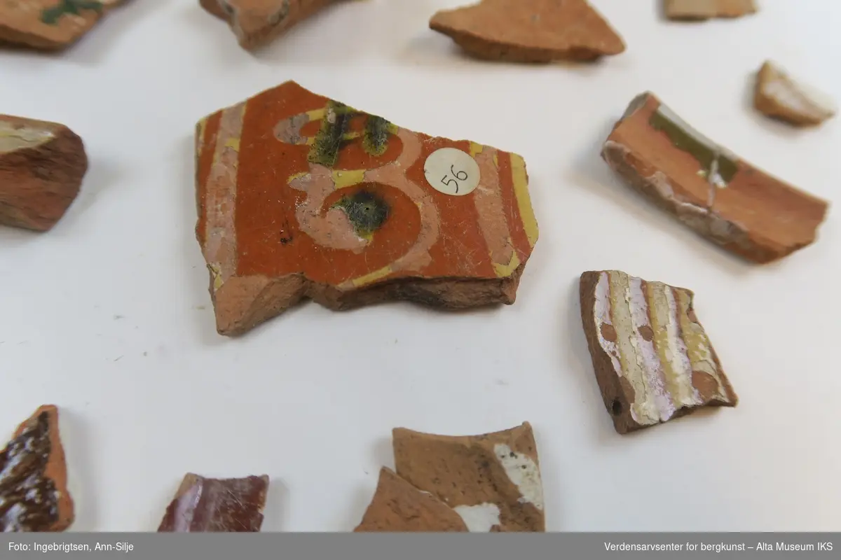 Et ark med mange keramikkfragmenter i ulike størrelser. Noen av fragmentene har rester etter glasur. 

Keramikkfragmentene varierer i størrelser fra 1,5 cm til 5,5 cm i lengde.