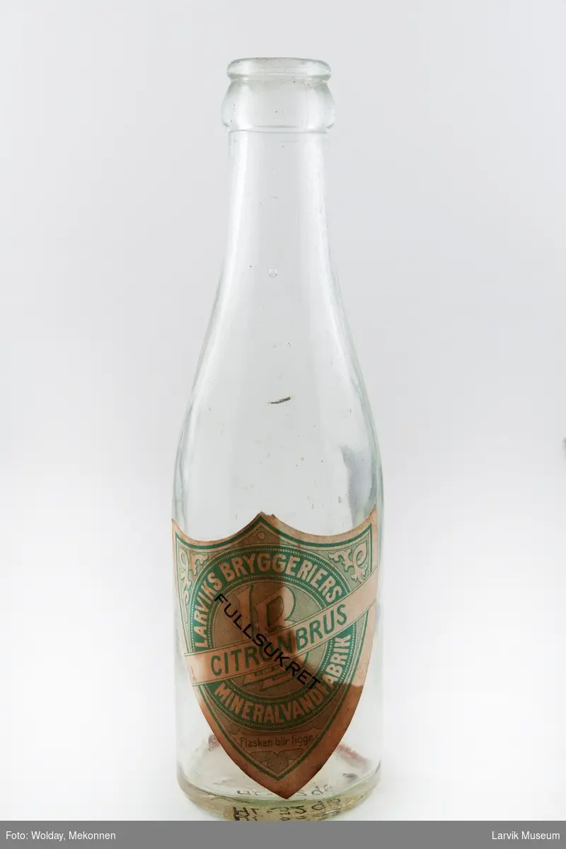 Flasken er blank med lys grønn og hvit etikett tekst etikett: Fullsukret citronbrus