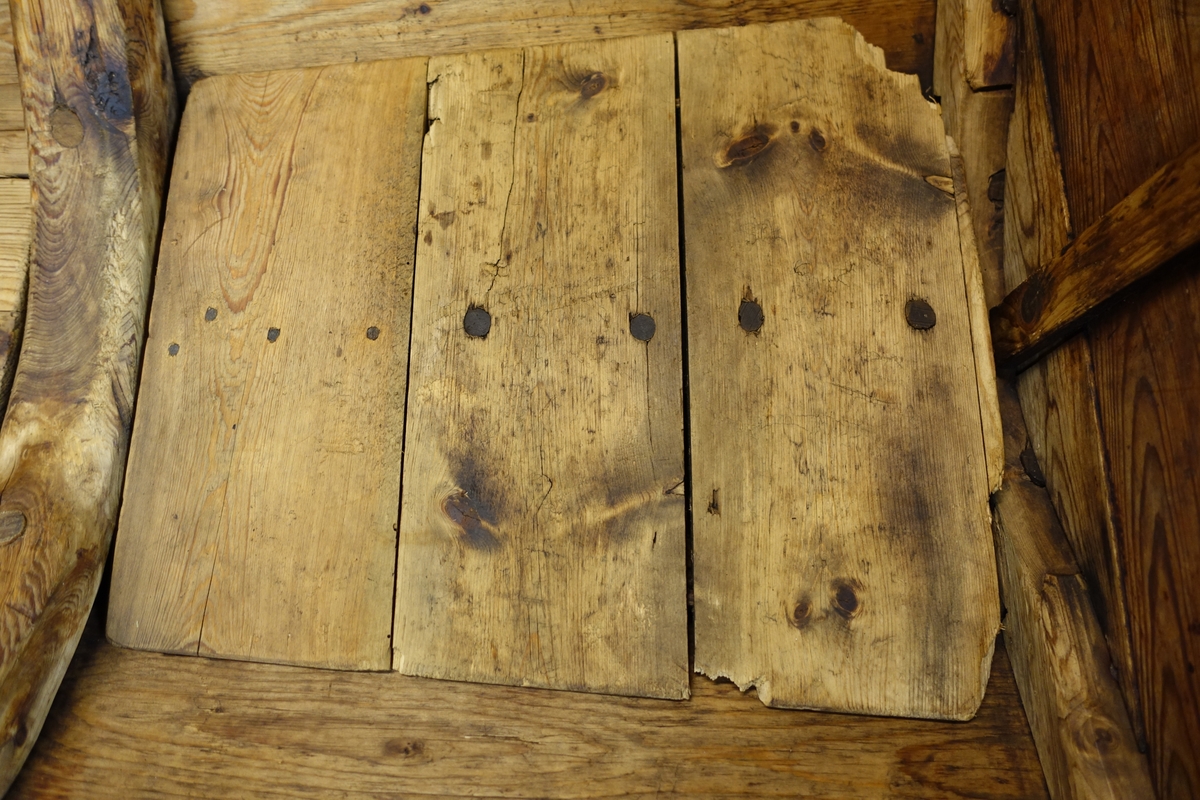 Tre høvla planker som er satt fast til en tversgående planke ved hjelp av trenagler og spiker