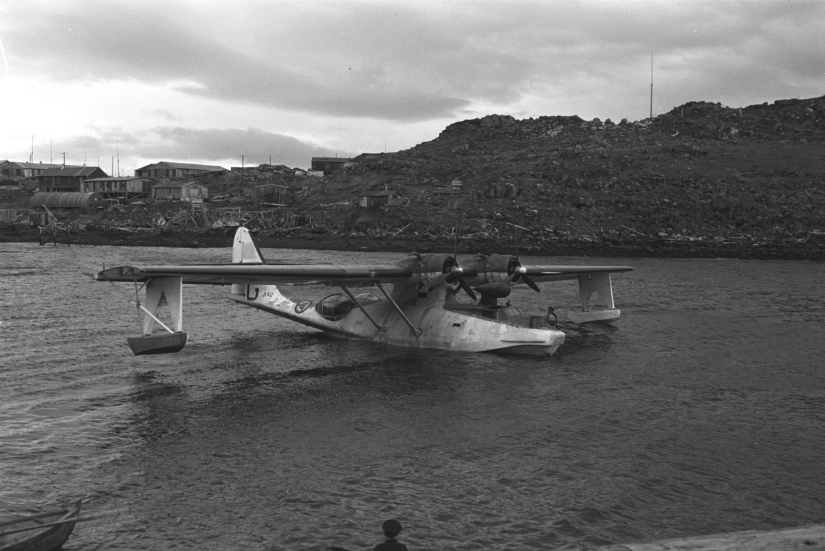 Gjenreisning i Honningsvåg. En Catalina-flybåt i havn. I bakgrunnen brakkebebyggelsen. 1946/47.