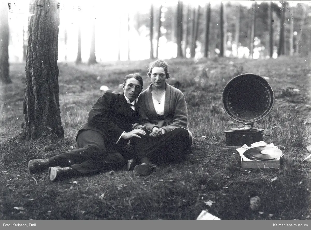 Musikstund i tallskogen. Emil Karlssons bror Sixten tillsammans med okänd flicka lyssnande till musik från trattgrammofon.