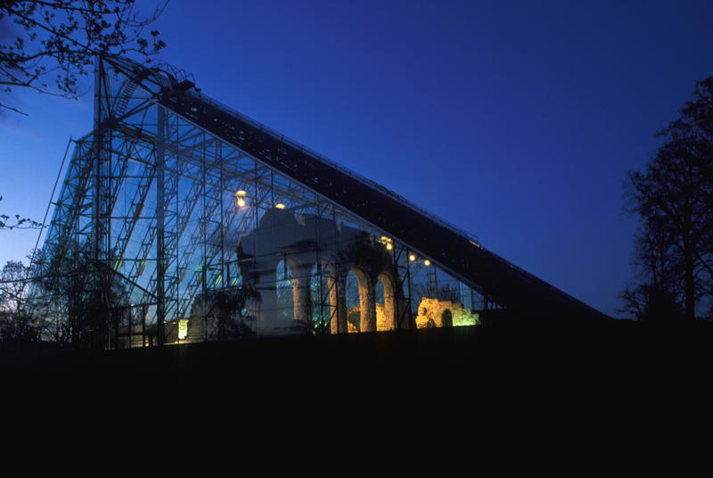 Domkirkeruinen under vernebygget i glass og stål er delvis opplyst og delvis i silhuett mot en mørkeblå kveldshimmel. (Foto/Photo)