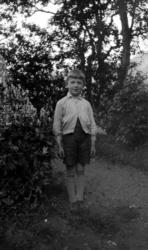 En Sverdrup-gutt (?) står rett for kamera i en hage. Fra Nor